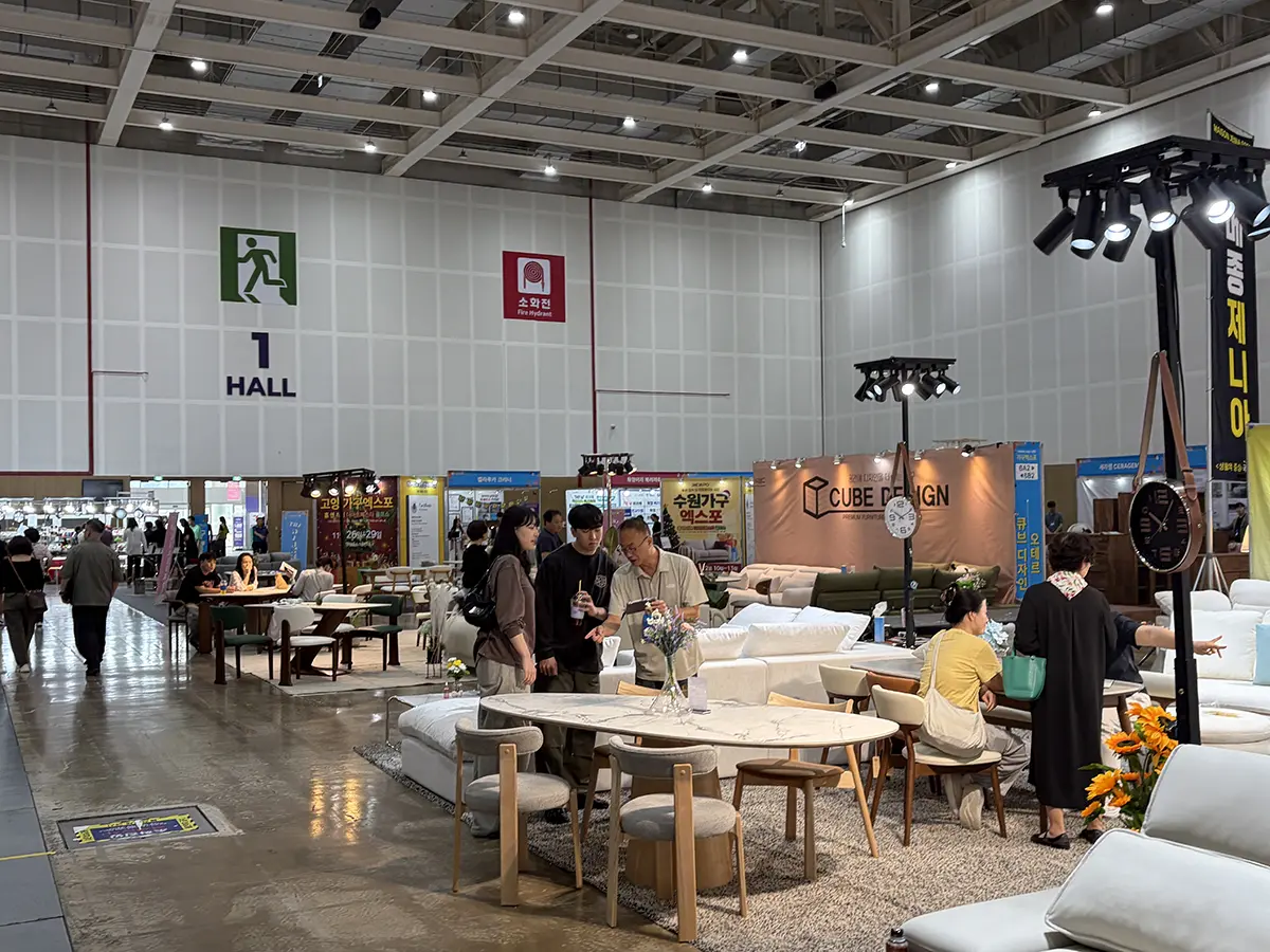 Furniture showroom at a trade fair with sofas tables and visitors browsing rows of displays