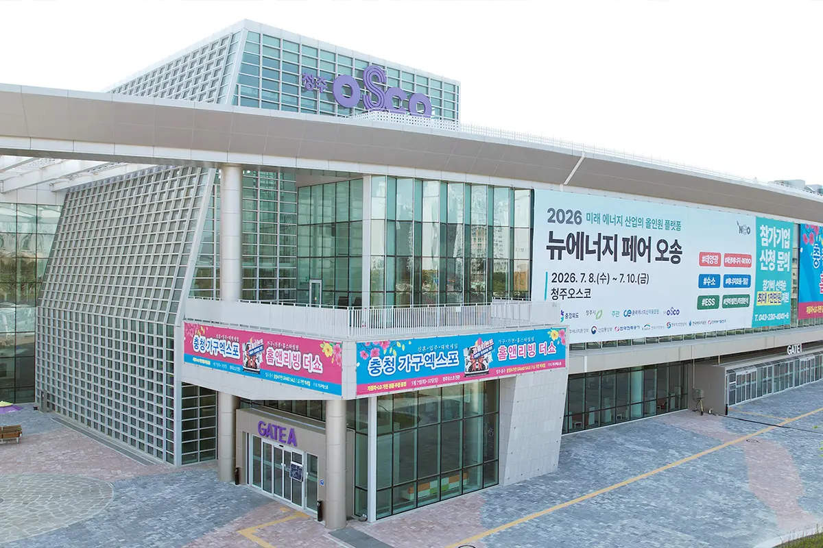 수원가구엑스포전시스케치08 수원 가구엑스포 Modern glass clad exhibition hall with a large Korean banner advertising the 2026 New Energy Fair and colorful signs along the balcony entrance labeled GATEA below the banners