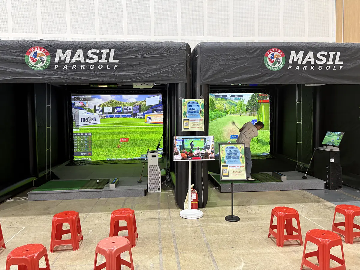 Two MASIL Park Golf simulators with large screens a golfer swings on the right bay while the left bay shows a course