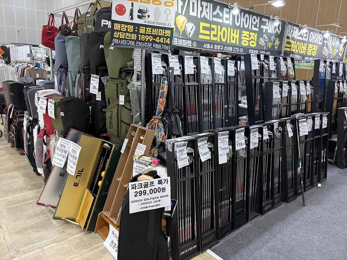 Indoor golf shop display featuring rows of golf clubs bags and price tags with Korean signage advertising sales
