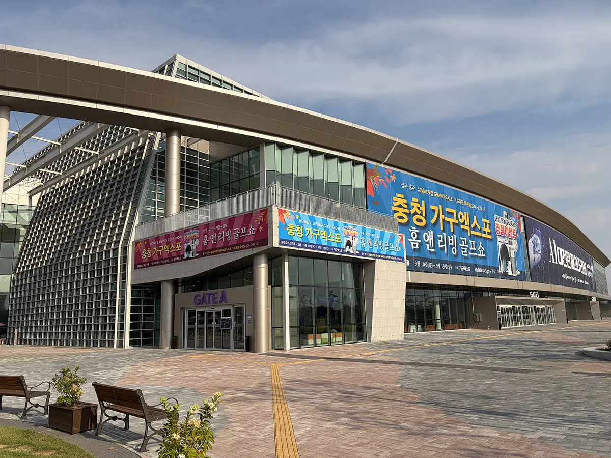Modern glass fronted building with colorful banners along the facade and a Gate A entrance